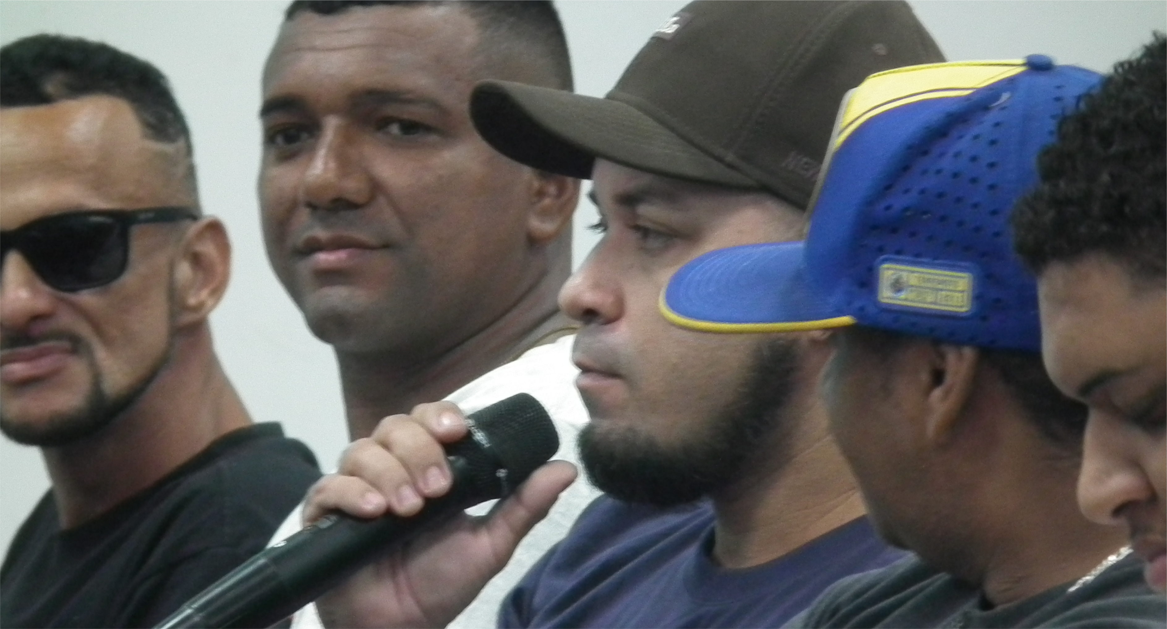 Alê Candido está realizando perguntas segurando o microfone aberto ao público.